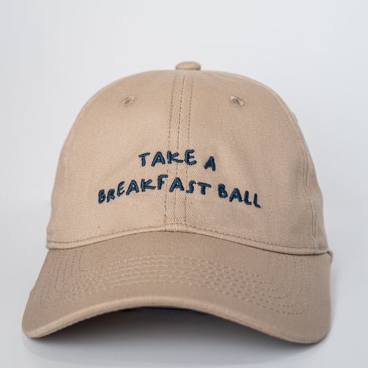 Beige cap with 'Take a Breakfast Ball' text on a white background