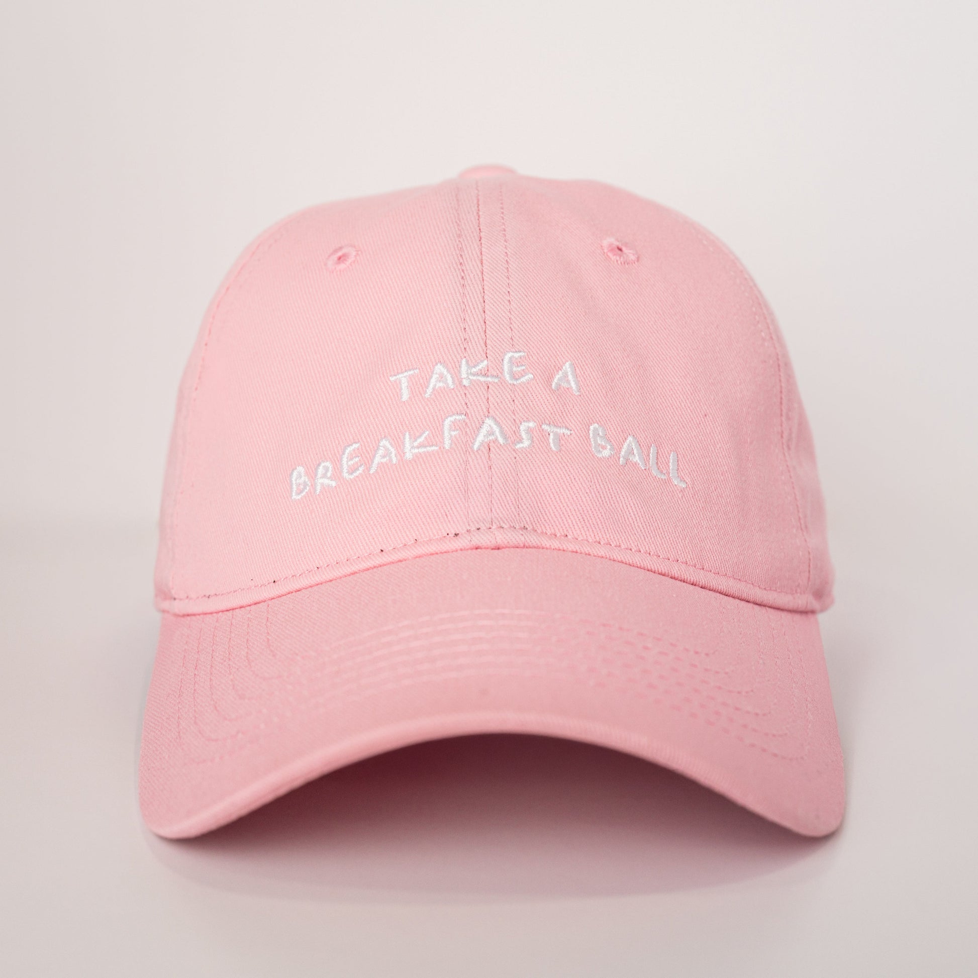 Pink cap with 'Take a Breakfast Ball' text on a light gray background