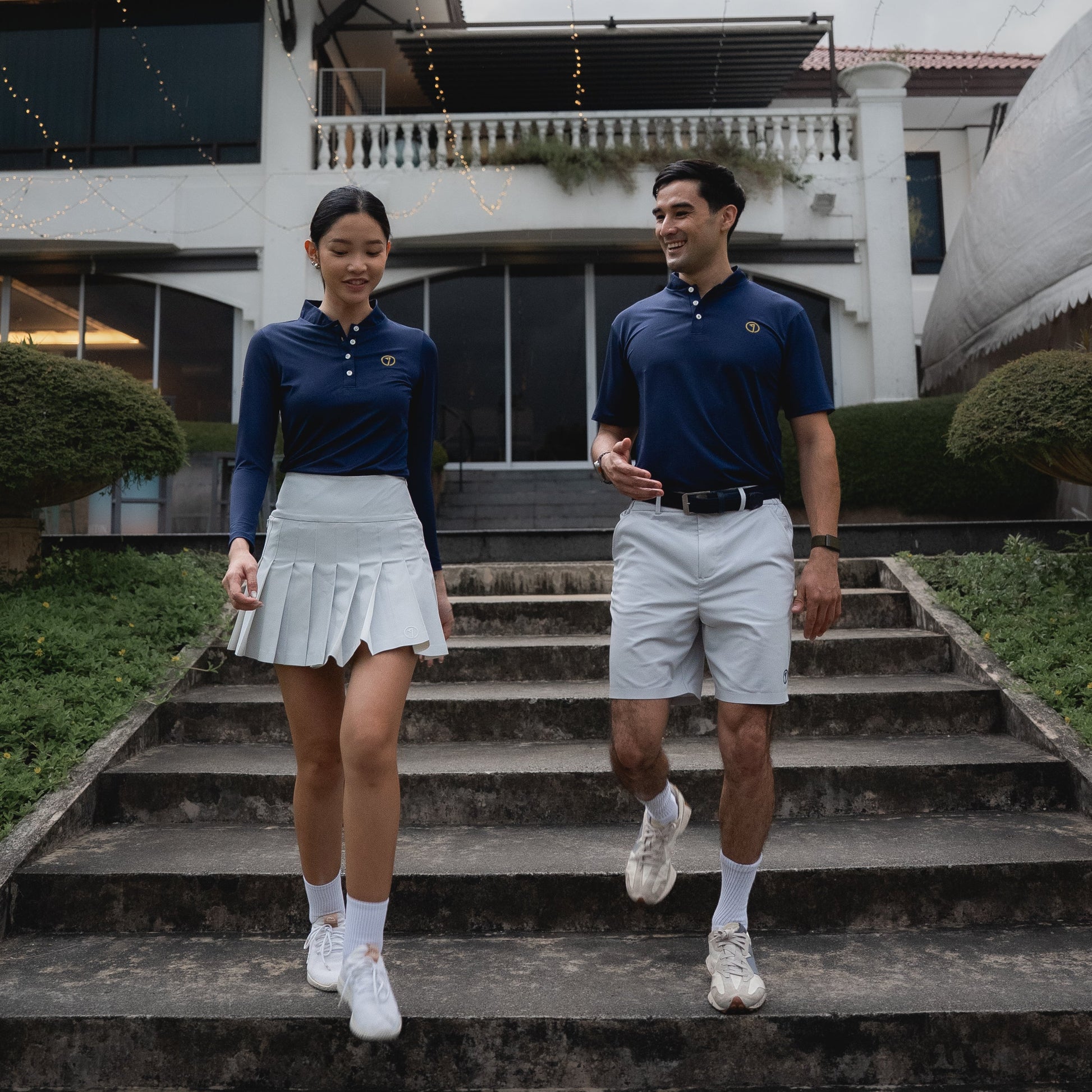 Two people in matching outfits walking up a set of stairs.
