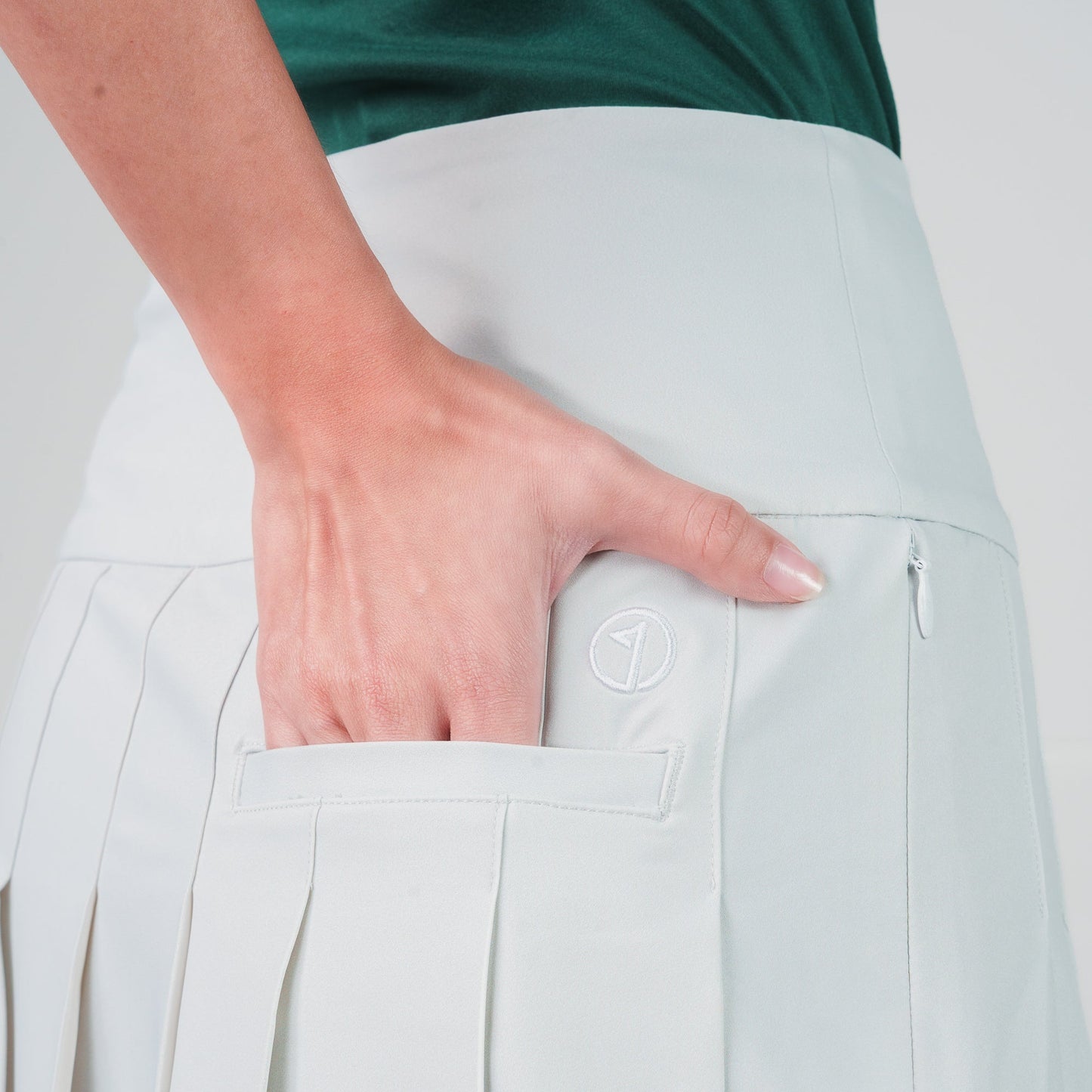 Light gray pleated skirt with a person wearing it on a plain background