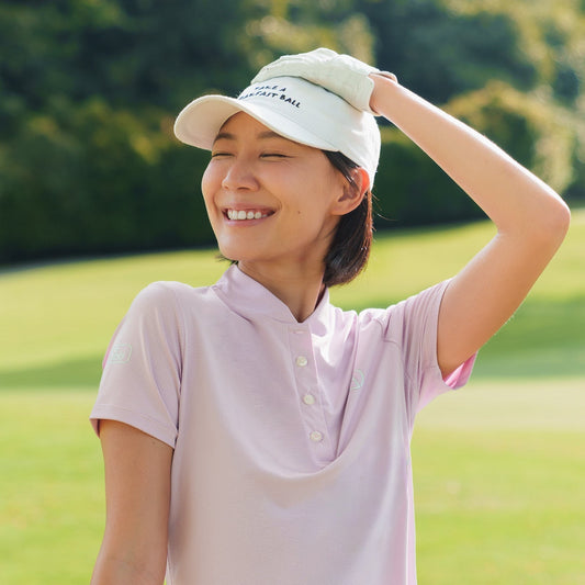 Woman in pink outfit on a golf course with greenery in the background