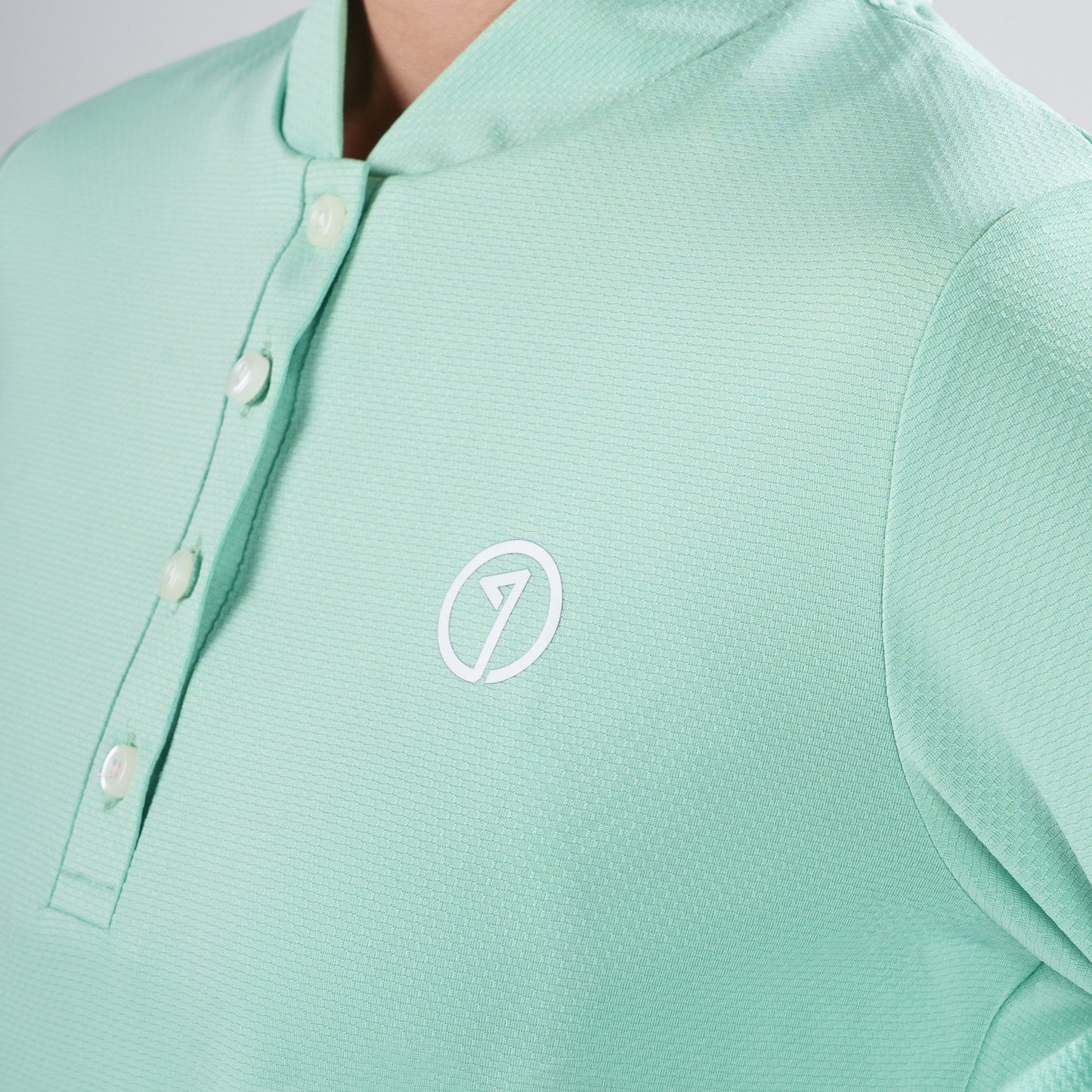 Mint green polo shirt with a logo on a neutral background