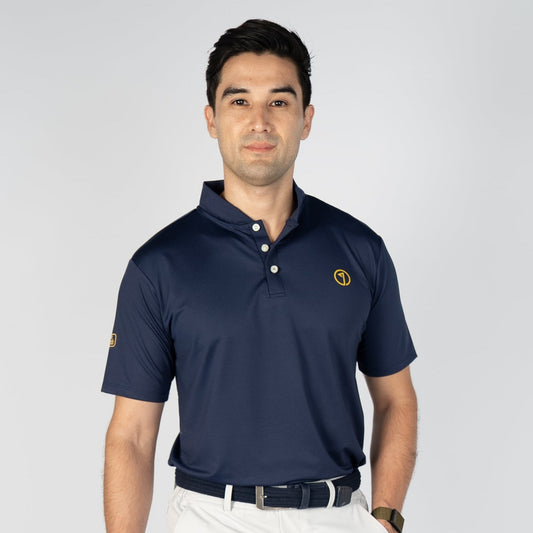 Man wearing a navy polo shirt, white shorts, and white shoes on a white background