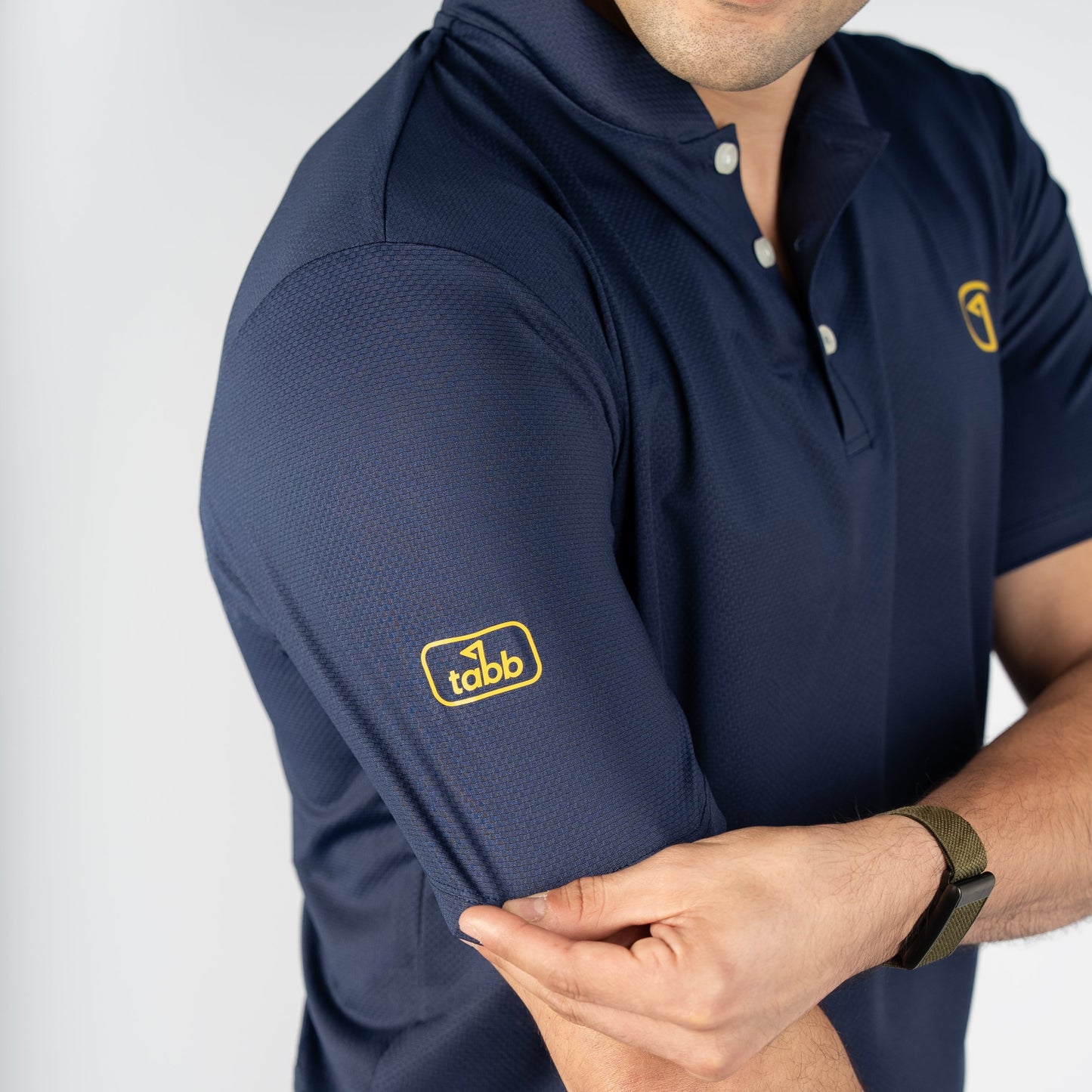 Man wearing a navy blue polo shirt with a logo on a white background
