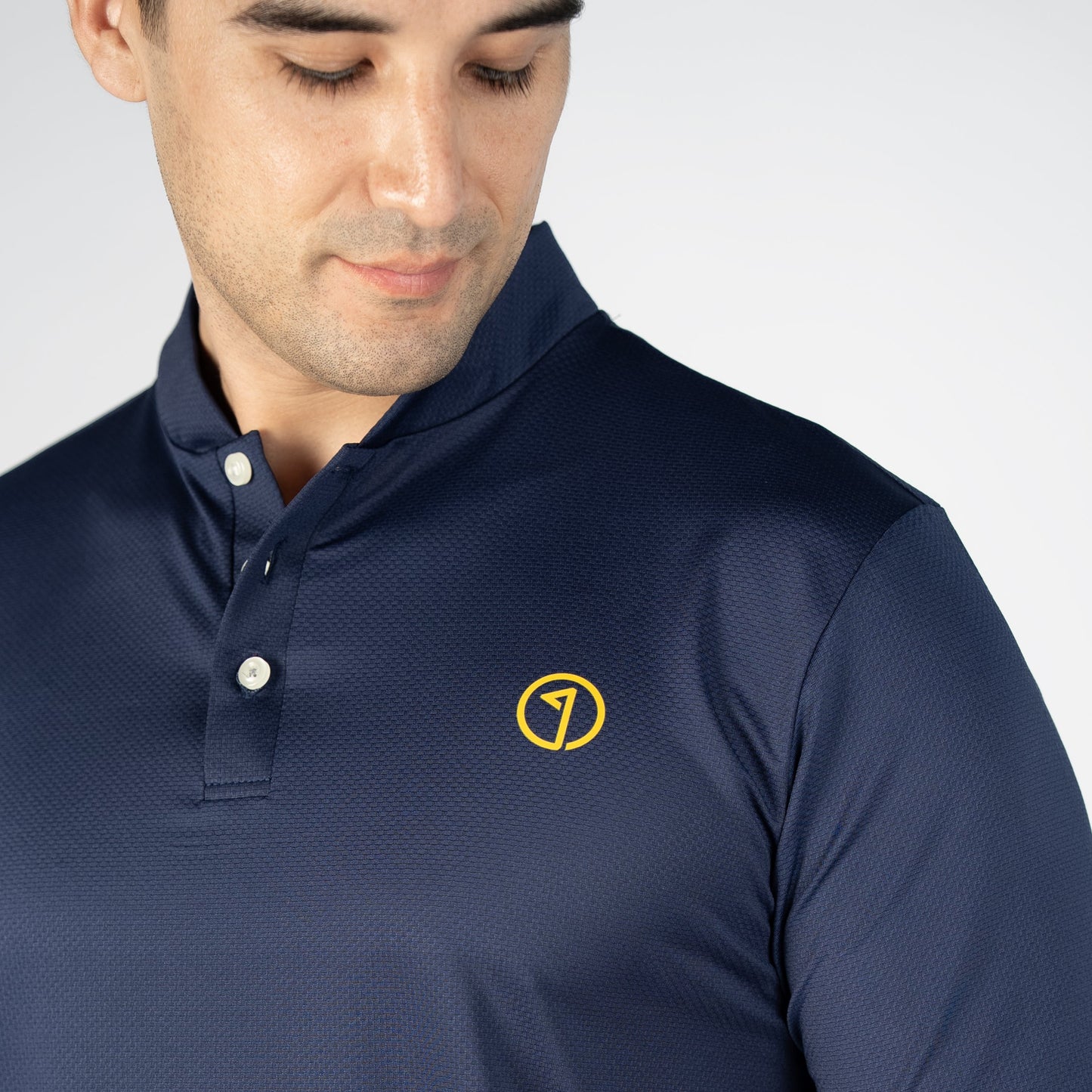 Man wearing a navy blue polo shirt with a yellow logo on a white background