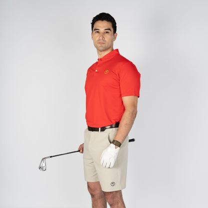 Man in red polo shirt and beige shorts holding a golf club on a white background