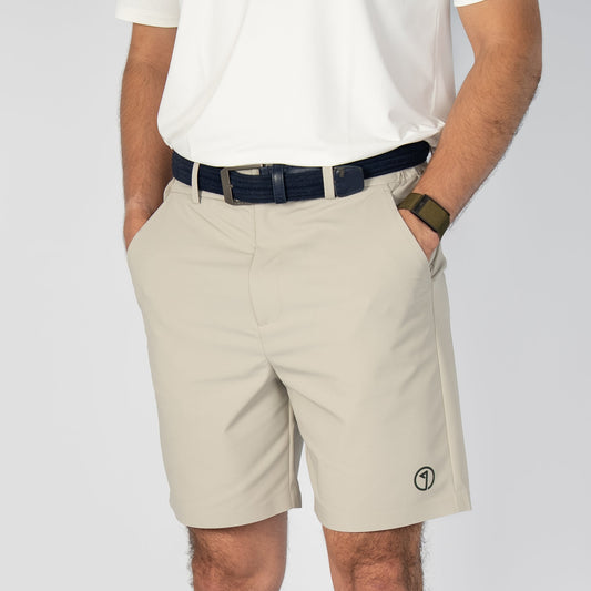 Person wearing beige shorts, white shirt, and sneakers on a plain background