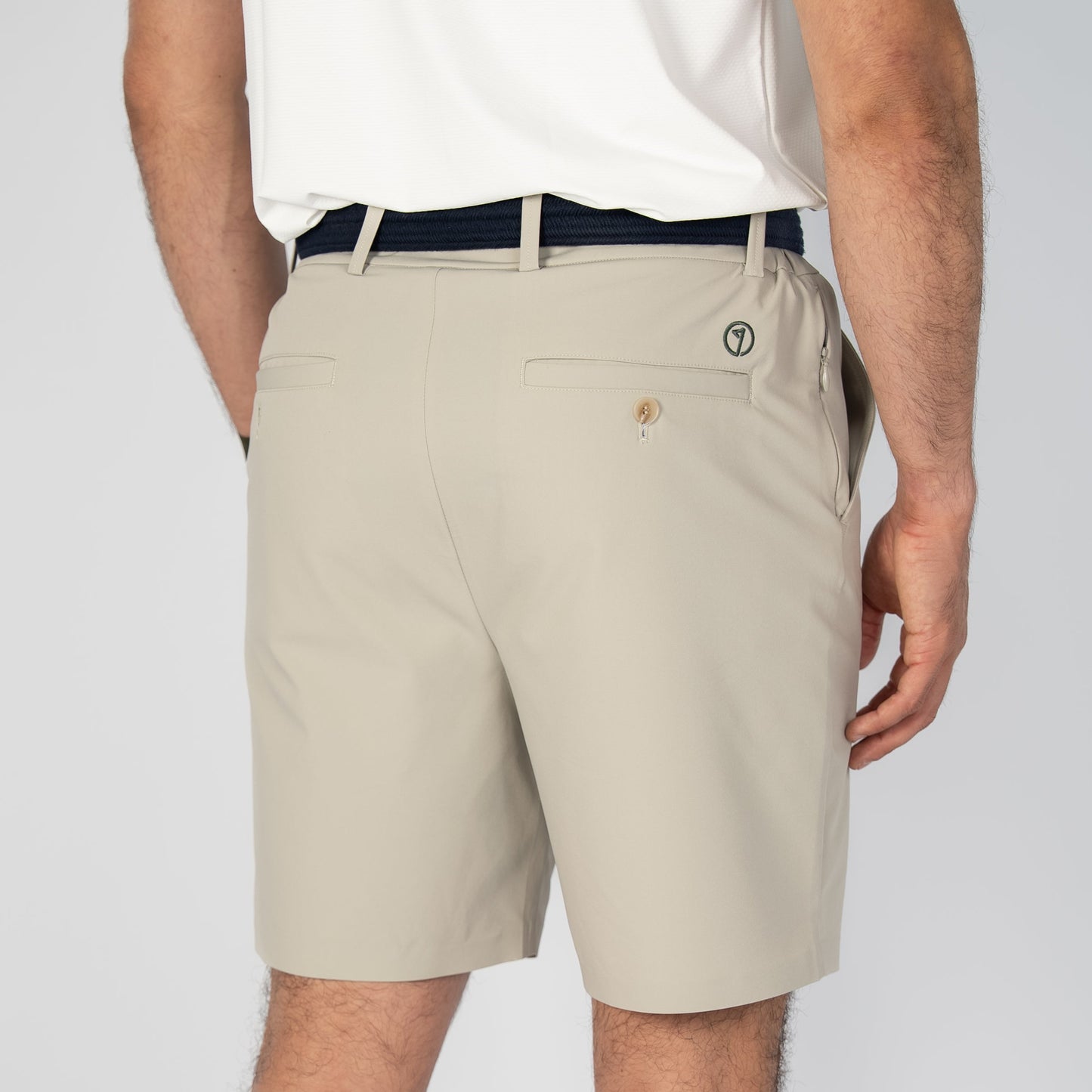 Person wearing beige shorts and a white shirt on a plain background
