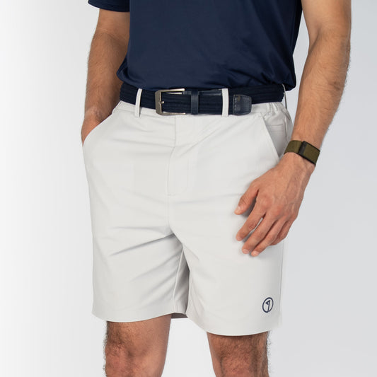 Person wearing light-colored shorts, a navy shirt, and white socks on a plain background