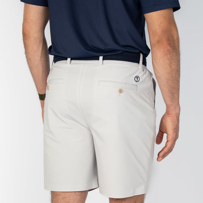 Person wearing beige shorts and a navy shirt on a white background