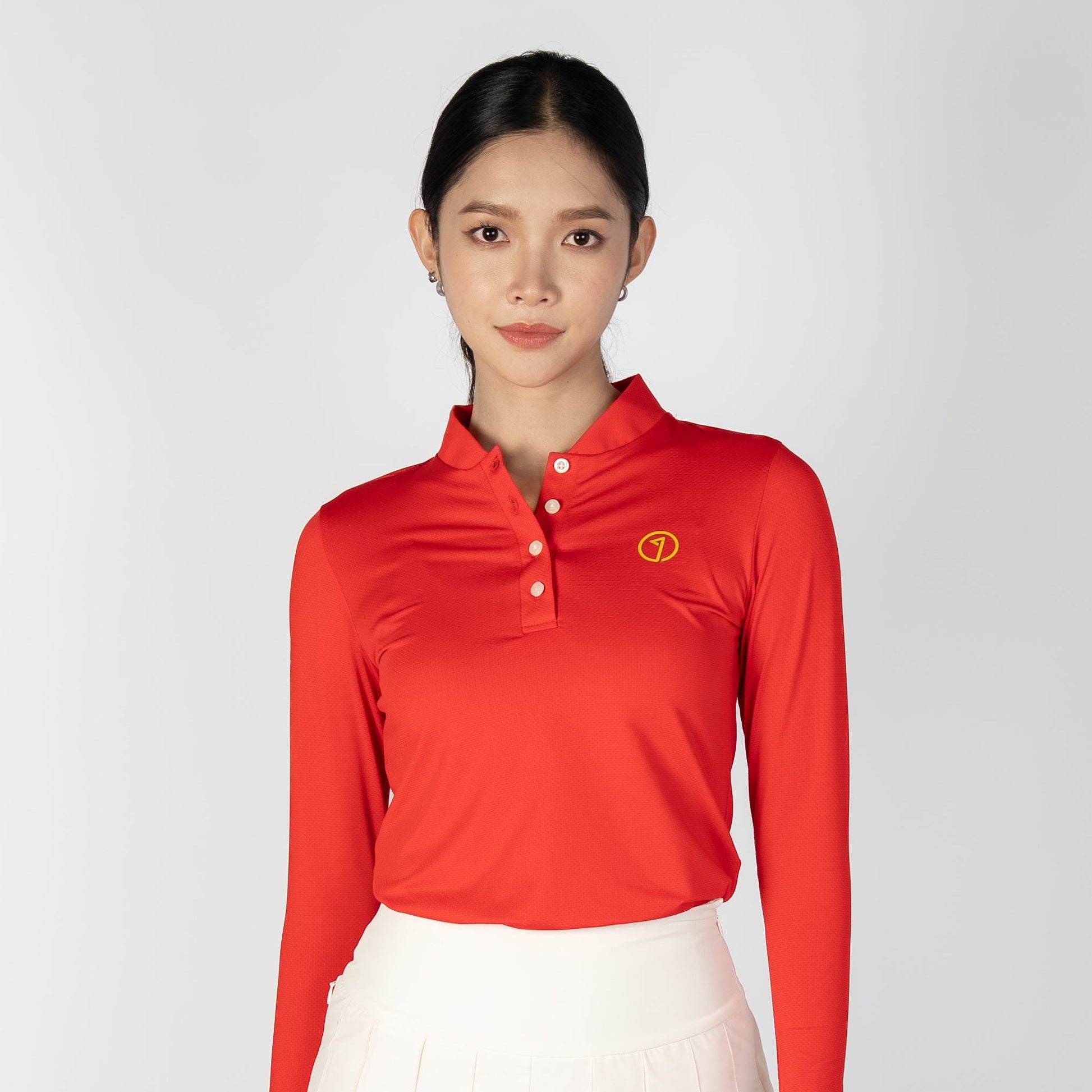 Woman wearing a red long-sleeve top and white pleated skirt on a white background