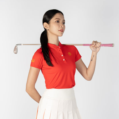 Woman in red polo shirt and white skirt holding a golf club on a white background